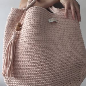 Duża torba shopperka w kolorze pudrowego róż€ trzymana przez modelkę.