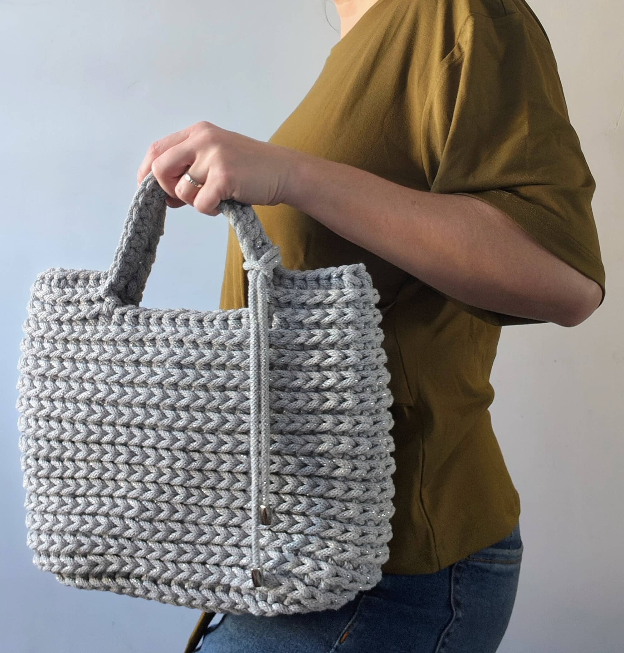 Stylizacja modowa z modelką trzymającą małą szarą torebkę